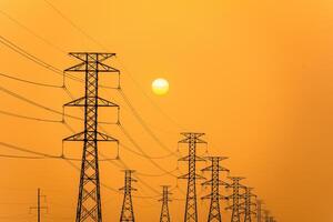elektriciteit pijlers tegen een kleurrijk geel zonsondergang. silhouet hoog Spanning elektrisch torens, macht lijnen. foto