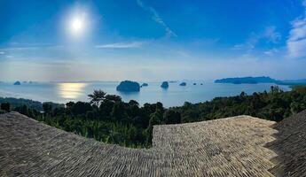 een adembenemend panoramisch visie van een sereen oceaan en verspreide eilanden van een tropisch heuveltop met traditioneel rieten daken foto