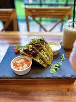 verrukkelijk fijnproever rundvlees taco's geserveerd met vers pico de gallo Aan een strak zwart leisteen dienblad, perfect voor een culinaire presentatie foto