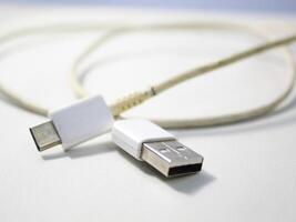 dichtbij omhoog de wit gebroken smartphone USB kabel Aan wit houten achtergrond. foto