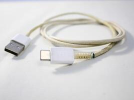 dichtbij omhoog de wit gebroken smartphone USB kabel Aan wit houten achtergrond. foto