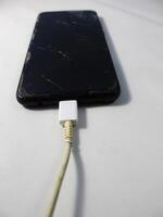 oud oplader kabel gebroken en smartphone, defecte opladen koord, verbinding verslechtering apparaat foto