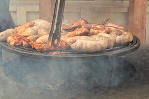 gebakken worstjes en kip Vleugels Aan barbecue rooster in de dorp. frituren vlees Aan Open brand. barbecue partij Aan achtertuin van land huis cabine. straat voedsel festival. huis Koken buitenshuis. picknick tijd foto