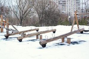 houten speelplaats gemaakt van natuurlijk milieuvriendelijk materiaal in openbaar stad park met sneeuw Bij winter tijd. modern veiligheid kinderen buitenshuis apparatuur. winter activiteiten. kinderen rust uit en spellen Aan Open lucht foto