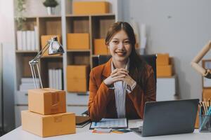 startende kleine ondernemer freelance, portret jonge vrouw aan het werk op kantoor aan huis, doos, smartphone, laptop, online, marketing, verpakking, levering, mkb, e-commerce concept foto