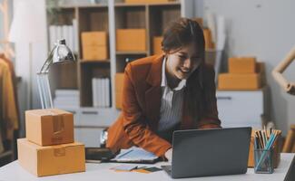 portret van startende eigenaren van kleine bedrijven vrouwelijke ondernemers werken aan kassabonnen en controleren online bestellingen om zich voor te bereiden op het inpakken van de dozen, verkopen aan klanten, mkb-bedrijfsideeën online. foto