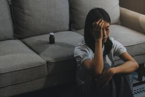 van streek vrouw gefrustreerd door probleem met werk of verhoudingen, zittend Aan bank, omarmen knieën, gedekt gezicht in hand, gevoel wanhoop en ongerustheid, eenzaamheid, hebben psychologisch probleem foto