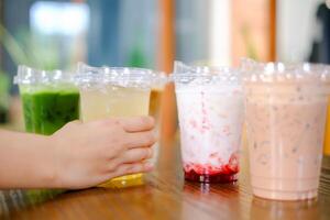 vrouw hand- houden plastic kop een veel van zoet of koffie Aan de houten tafel achtergrond in cafe restaurant, vieren, feesten, vergadering foto