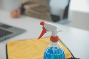 vrouw schoonmaak tafel gebruik makend van vod en verdeler Bij huis. foto