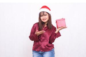 foto portret van mooi Aziatisch meisje in haar Jaren 20 draag- geschenk doos Bij Kerstmis de kerstman claus hoed modern glimmend rood overhemd kleding voorstellen glimlach doos Aan wit achtergrond voor Promotie en reclame