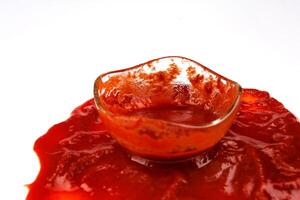 tomaat saus . glas kop met resterend ketchup en ketchup gemorst in de omgeving van het. foto