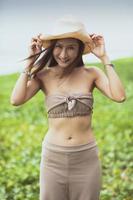 portret van een mooie Aziatische jongere vrouw met een groot lachend gezicht met gelukemotie op zeestrand foto