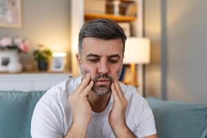 tand pijn en tandheelkunde. jong Mens lijden van vreselijk sterk tanden pijn, aanraken wang met hand. gevoel pijnlijk kiespijn. tandheelkundig zorg en Gezondheid concept. hoog resolutie foto