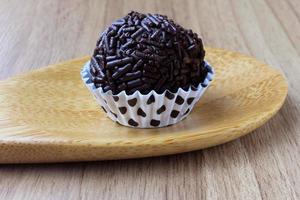 brigadeiro, brigadier, zoete chocolade typisch voor de Braziliaanse keuken bedekt met deeltjes, op een houten achtergrond. foto