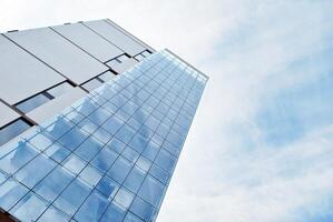 glas gebouw met transparant facade van de gebouw en blauw lucht. structureel glas muur reflecterend blauw lucht. abstract modern architectuur fragment. hedendaags bouwkundig achtergrond. foto