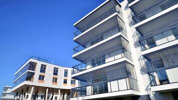 een appartement gebouw met een uniek bouwkundig oplossing. een modern woon- gebouw met een wit facade en staand Aan hoog beton pijlers. foto