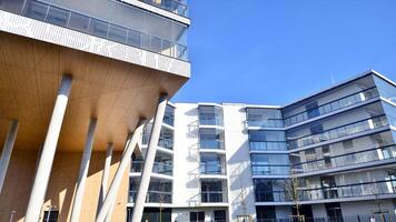 een appartement gebouw met een uniek bouwkundig oplossing. een modern woon- gebouw met een wit facade en staand Aan hoog beton pijlers. foto