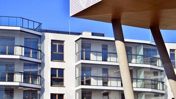 een appartement gebouw met een uniek bouwkundig oplossing. een modern woon- gebouw met een wit facade en staand Aan hoog beton pijlers. foto