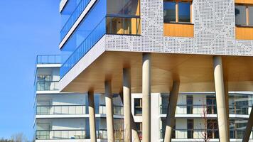 een appartement gebouw met een uniek bouwkundig oplossing. een modern woon- gebouw met een wit facade en staand Aan hoog beton pijlers. foto