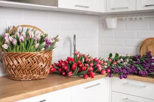 een groot aantal van tulpen van verschillend kleuren leugens in de keuken in de wasbak. bloemen in een mand foto