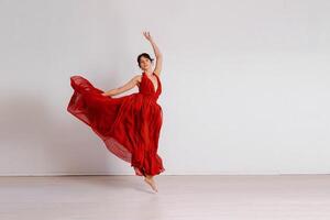 danser in een rood vliegend jurk. vrouw ballerina dansen Aan een wit studio achtergrond foto