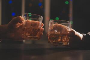 viering nacht, gieten whisky in een glas. geven naar vrienden wie komen naar vieren foto