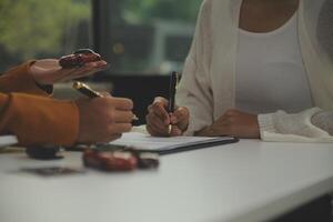 verzekering officieren hand- over- de auto sleutels na de huurder. hebben ondertekend een auto verzekering document of een huren of overeenkomst document buying of verkoop een nieuw of gebruikt auto met een auto foto