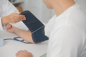 mannetje dokter toepassingen een bloed druk toezicht houden op naar controleren de lichaam druk en pulse van de patiënten wie komen naar de ziekenhuis voor controles, medisch behandeling en Gezondheid zorg concept. foto