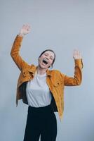 de mooi emotioneel Europese bruin haar vrouw met gezond schoon huid, charmant glimlach, gekleed in gewoontjes licht kleren, luistert en geniet muziek- Aan hoofdtelefoons met tablet Aan een wit achtergrond. foto