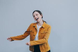 de mooi emotioneel Europese bruin haar vrouw met gezond schoon huid, charmant glimlach, gekleed in gewoontjes licht kleren, luistert en geniet muziek- Aan hoofdtelefoons met tablet Aan een wit achtergrond. foto