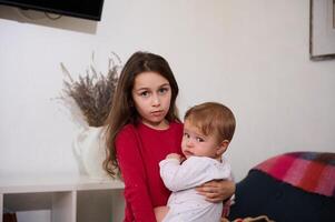 Kaukasisch schattig kind meisje knuffelen haar weinig baby broer Bij huis. de concept van familie relaties en zorg. Internationale kinderen dag. broer en zus samen foto