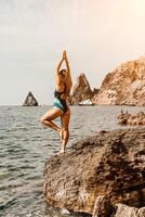 yoga Aan de strand. een gelukkig vrouw mediteren in een yoga houding Aan de strand, omringd door de oceaan en rots bergen, bevorderen een gezond levensstijl buitenshuis in natuur, en inspirerend geschiktheid concept. foto