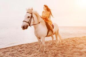 een vrouw in een jurk staat De volgende naar een wit paard Aan een strand, met de blauw lucht en zee in de achtergrond. foto