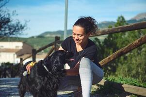 gelukkig vrouw strelen haar hond, een zwart cocker spaniel terwijl wandelen samen in de natuur foto