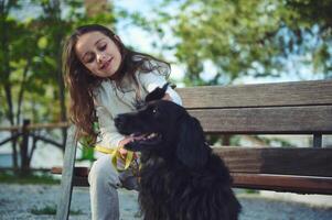 weinig meisje en haar hond gedurende een wandelen buitenshuis. de concept van liefde, zorg en empathie voor dieren foto