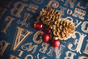 christams gouden dennenappel en rode glazen bol decoratie op vintage type patroon tafel. foto