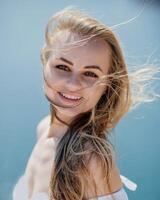 portret van een blond vrouw Bij de zee, een vrouw maakt foto's voor geheugen van een reis naar de zee naar tonen naar vrienden. foto