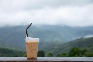 kop van bevroren koffie Aan een houten terras met berg visie in achtergrond. foto