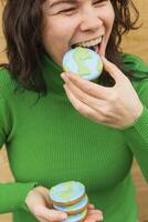 aarde dag concept. vrouw bijt in een koekje in de vorm van de aarde. foto