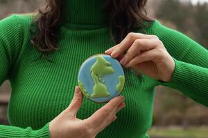 aarde dag concept. peperkoek in de vorm van een planeet in de handen van een vrouw. foto