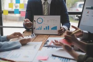 co-werkconferentie, zakelijke teamvergadering aanwezig, investeerderscollega's bespreken nieuw plan financiële grafiekgegevens op kantoortafel met laptop en digitale tablet, financiën, boekhouding, investeringen. foto