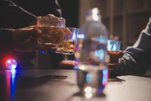 viering nacht, gieten whisky in een glas. geven naar vrienden wie komen naar vieren foto