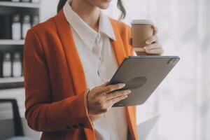 portret van jonge aziatische vrouw hand freelancer werkt haar baan op computer tablet in moderne kantoren. doen van boekhoudkundige analyse rapport vastgoedinvesteringsgegevens, financiële en fiscale systemen concept. foto