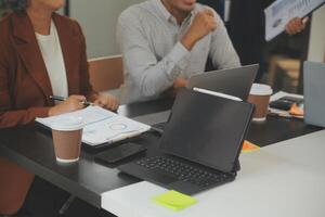 bedrijf team vergadering werken met nieuw opstarten projecteren, discussie en analyse gegevens de grafieken en grafieken. digitaal tablet, rekenmachine, laptop computer gebruik makend van, bedrijf financiën en accounting concept. foto