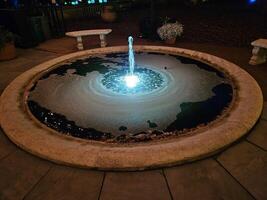 een gemakkelijk water fontein met helder lichten Bij nacht in een historisch huis en tuin foto