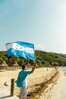 een persoon Holding en golvend Honduras vlag in een strand. patriottisme concept. foto