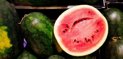 voor de helft van vers watermeloen zetten in zwart plastic houder Bij supermarkt of fruit straat markt. biologisch of gezond voedsel concept foto