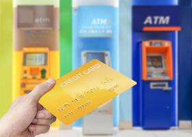 hand- Holding mockup goud credit kaart met kleurrijk contant geld machine achtergrond foto