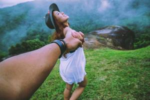 minnaar vrouwen en mannen aziaten reizen ontspannen in de vakantie. hand in hand lopen op het gazon. wilde natuur hout op de berg. foto