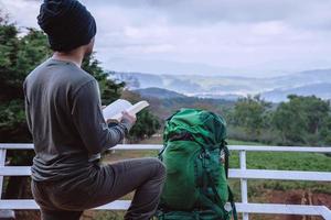 aziatische man reizen ontspannen in de vakantie. stoelen ontspannen boeken lezen bij het uitzichtpunt op de berg. bij doi inthanon chiangmai in thailand. foto